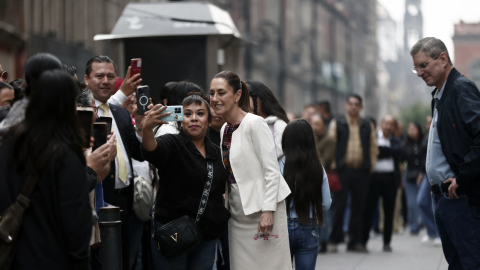 272 / 5.000La presidenta de México, Claudia Sheinbaum (C), posa para una selfie con un partidario mientras su esposo, Jesús María Tarriba, observa a su llegada para votar en un centro de votación durante las primeras elecciones mexicanas del mundo para todos los jueces y magistrados en la Ciudad de México el 1 de junio de 2025.