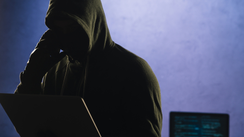Imagen referencial de un ciberdelincuente frente al computador y con teléfono a mano, 6 de junio de 2025.