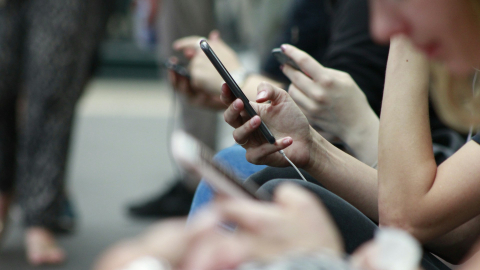 Fotografía referencial de un grupo de jóvenes que usan sus celulares para navegar en redes sociales.