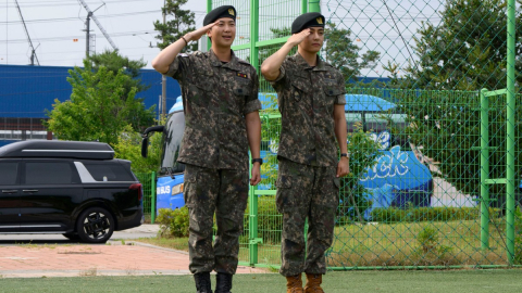 Los miembros de la banda BTS, RM y V, saludan después de su liberación de 18 meses de servicio militar, el 10 de junio de 2025, en Corea del Sur.