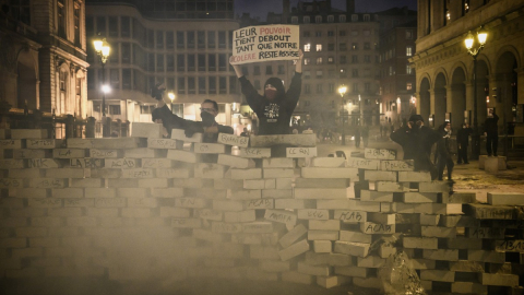Un manifestante detrás de una barricada sostiene una pancarta que dice: "Su poder se mantiene en pie mientras nuestra rabia se mantiene sentada", en medio de protestas por "el alto costo de la vida" en Lyon, Francia, el 17 de octubre de 2026.