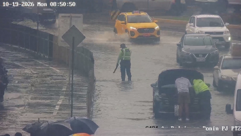 Un agente de la ATM en una de las avenidas inundadas en el norte de la ciudad, y varios carros varados, Guayaquil, el 19 de octubre de 2026.