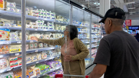 Consumidores en la sección lácteos de un supermercado.