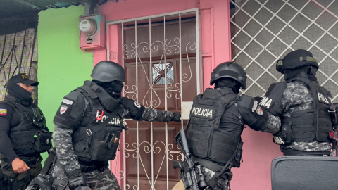 Policías de un equipo táctico fuerzan la puerta de una vivienda durante una intervención del Bloque Seguridad en Socio Vivienda 2, en el noroeste de Guayaquil, la madrugada y mañana de este domingo 25 de octubre de 2025.