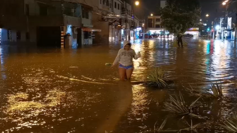 Una mujer camina en una calle cubierta por el agua en Guayaquil, el 26 de octubre de 2026.