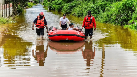 Bomberos de Machala evacúan a un adulto mayor por las inundaciones en la zona norte de la ciudad, el 27 de octubre de 2026.