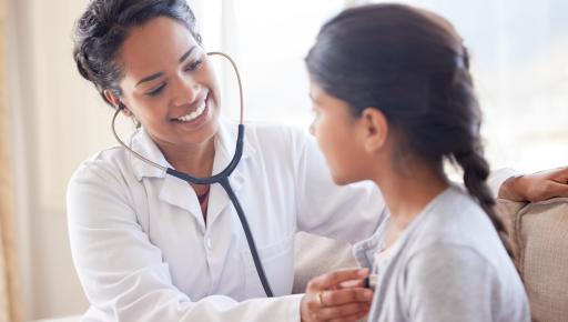 Médico examinando a una niña con un estetoscopio.