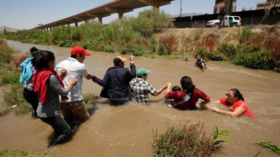 Migrantes hondureños y salvadoreños hacen una cadena para cruzar el Río Bravo en la frontera entre México y Estados Unidos.