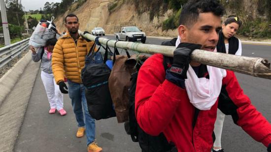 Un grupo de migrante venezolanos camina con su equipaje en la carretara que une a Tulcán con el puente fronterizo de Rumichaca.