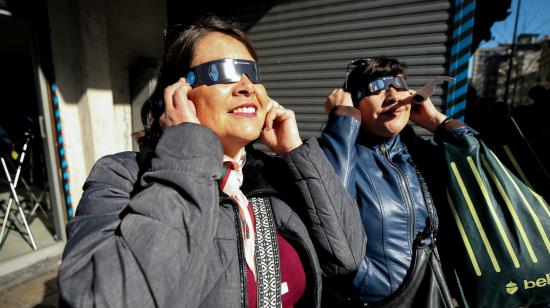 Mujeres prueban gafas especializadas para ver el eclipse de sol total, en Santiago (Chile). 