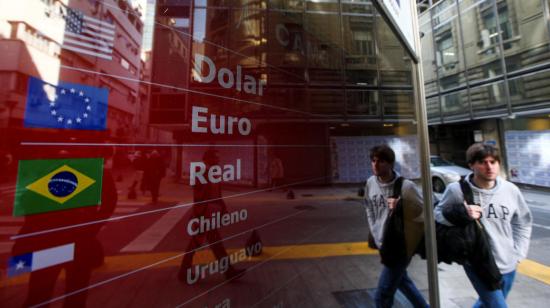 Un hombre camina frente a una casa de cambios en Buenos Aires, donde se exhiben las cotizaciones de distintas monedas.