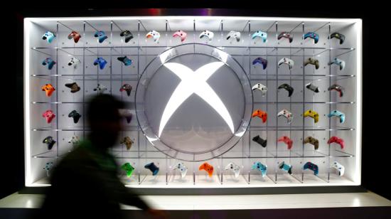 Un hombre camina frente a un exhibidor de controles para las consolas Xbox.