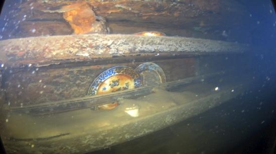 Fotografía cedida por el servicio de Parques de Canadá donde se muestran unos platos y otros artefactos en estantes al lado de una mesa de comedor para miembros de la tripulación de menor rango en el interior del navío HMS Terror. El Gobierno de Canadá dio a conocer este miércoles las primeras imágenes del interior del navío HMS Terror, un buque del explorador británico John Franklin que desapareció en el Ártico en 1846 cuando intentaba atravesar el Pasaje del Noroeste.