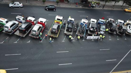 Agentes de la Agencia Nacional de Tránsito junto a las grúas y algunos de los vehículos retenidos por circular sin placas.