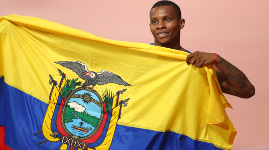 Álex Quiñónez celebra su tercer lugar en el Mundial de atletismo en Doha, con la bandera de Ecuador. 