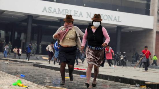 Manifestantes indígenas huyen de los gases lacrimógenas que lanzó la policía para recuperar el control de la Asamblea.