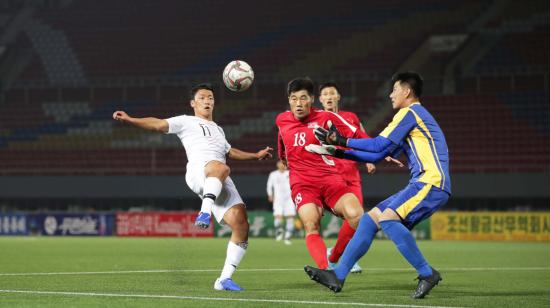 Hwang Hee-chan (blanco) de Corea del Sur, pelea una pelota ante dos jugadores del Corea del Norte. 