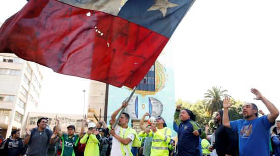 Trabajadores sostienen una bandera mientras protestan por las medidas económicas en Chile. 