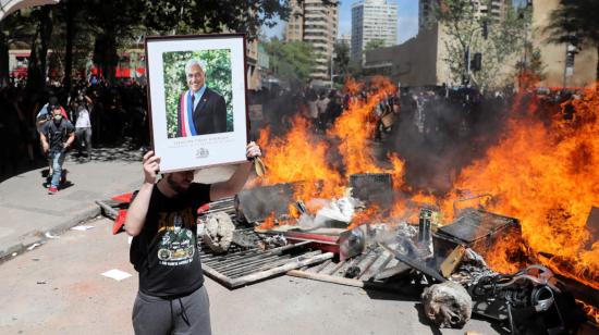 Un manifestante exhibe un cuadro del presidente Sebastián Piñera durante las protestas en Santiago.