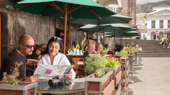 Una pareja de turistas ve un mapa en una de las cafeterías ubicadas en la Plaza de La Independencia, en el Centro Histórico de Quito. 