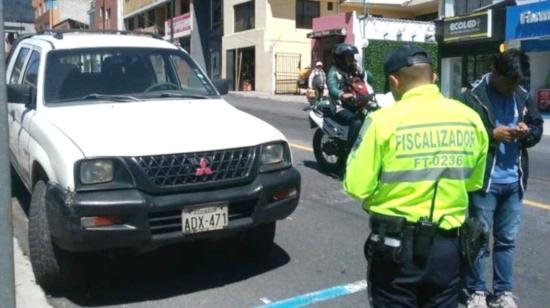 Un agente de tránsito revisa el buen uso del sistema de estacionamiento Zona Azul en Quito, en una fecha no determinada.