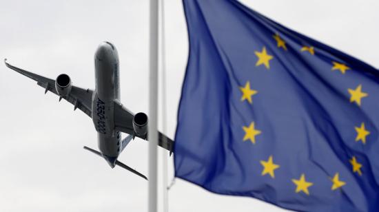 Un avión vuela junto a una bandera de la Unión Europea en el aeropuerto Le Bourget, de París, Francia.