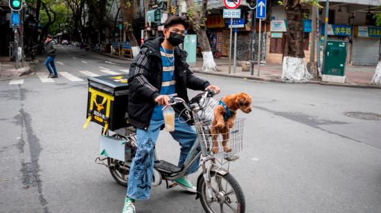 Un hombre con una máscara sanitaria lleva a su perro en la cesta de su bicicleta en Cantón, provincia de Guangdong (China).