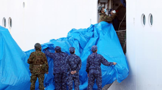 Militares japoneses aíslan un paso para que los pasajeros del crucero contagiados de coronavirus sean trasladados a una casa de salud.