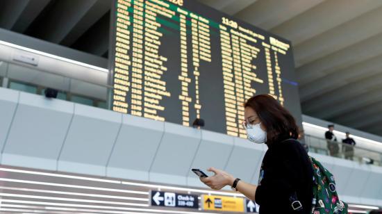 Una turista lleva una máscara de protección mientras utiliza su teléfono en el aeropuerto de Roma, en Italia.