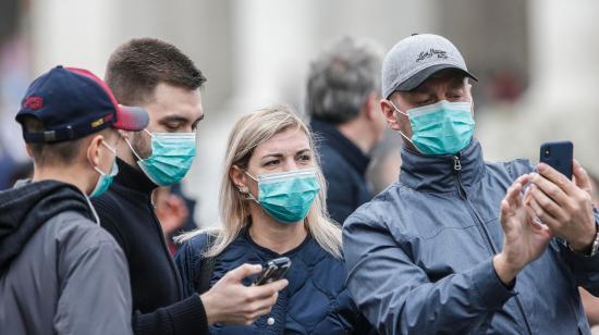 Varios asistentes llevan mascarillas para protegerse del coronavirus mientras asisten a la oración del Angelus, oficiada por el papa Francisco, en la plaza de San Pedro del Vaticano.