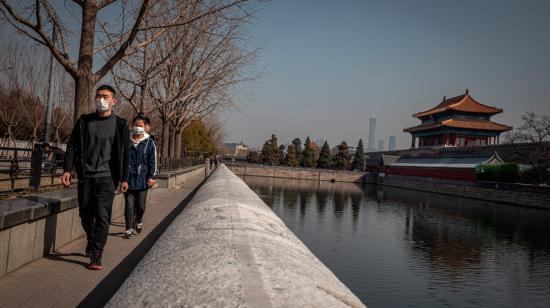 Las personas que llevan máscaras faciales protectoras caminan cerca de la Ciudad Prohibida, en Beijing, China, el 11 de marzo de 2020.