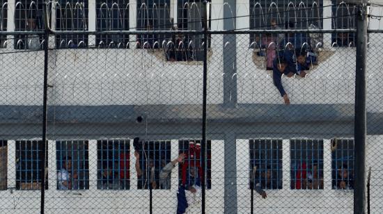 Reclusos se asoman en ventanas este domingo luego de un motín, en cárcel la Modelo de Bogotá.