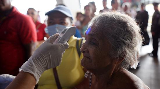 Personal médico controla la temperatura de los pasajeros en la Terminal Terrestre de Guayaquil, el 16 de marzo de 2020.