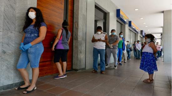 Debido al coronavirus, personas guardan distancia a la entrada de un local comercial en Guayaquil, el 24 de marzo. 