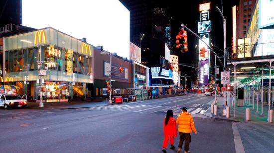 Dos personas caminan en el Times Square de Nueva York, ciudad donde solo están abiertos locales de productos esenciales desde el pasado 20 de marzo. 