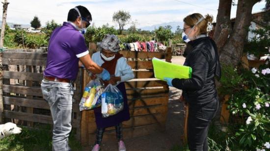 Funcionarios del MIES entregan alimentos a una habitante de Pichincha, el 26 de marzo de 2019.