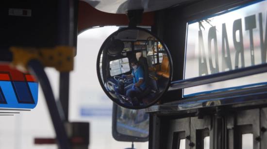 Un conductor de bus toma precauciones, como usar guantes y mascarilla, para cumplir con su labor.