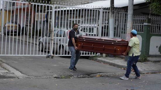 Un familiar y el trabajador de una funeraria cargan el ataúd de una mujer que falleció en casa por posible coronavirus el 31 de marzo de 2020 en Guayaquil.