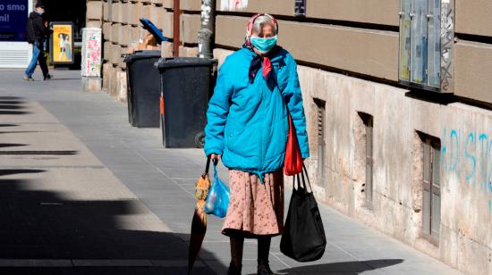 Señora caminando con bolsas de comida en las calles de Bélgica, este 9 de abril.