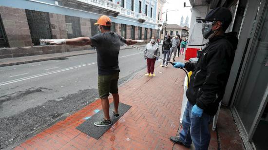 Un empleado desinfecta a un ciudadano antes de entrar a un supermercado en Quito este 17 de abril de 2020.