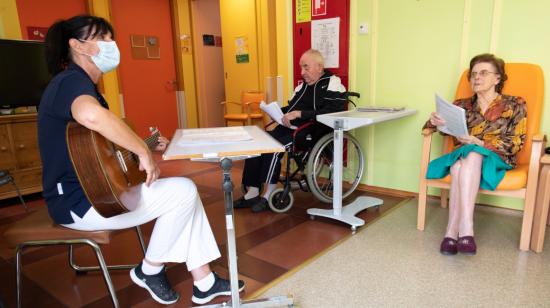 La animadora Mirella Raymond (izq.) Toca la guitarra y canta con los residentes de hogares de ancianos, que sobrevivieron a COVID-19, durante un estado de emergencia en Chateau-d'Oex, Suiza, el 20 de abril de 2020.