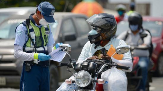 Un miembro de la Autoridad de Tránsito Municipal de Guayaquil revisa el salvoconducto de un motociclista en el puente de la Unidad Nacional. 