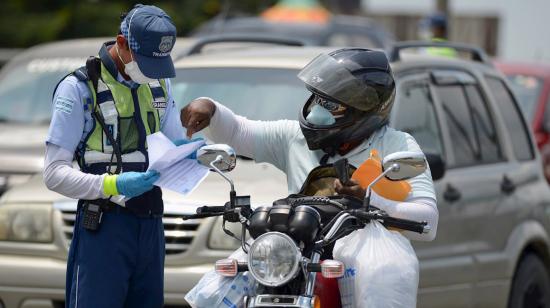 Un agente de tránsito revisa salvoconductos en el puente de la Unidad Nacional, en Guayaquil, el 23 de abril de 2020.