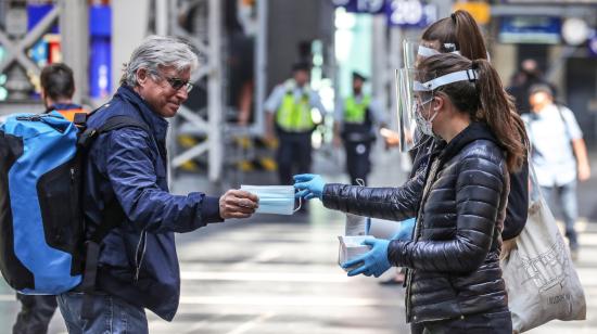 Dos mujeres entregan una mascarilla a un señor, el 27 de abril, en un aeropuerto de Alemania.