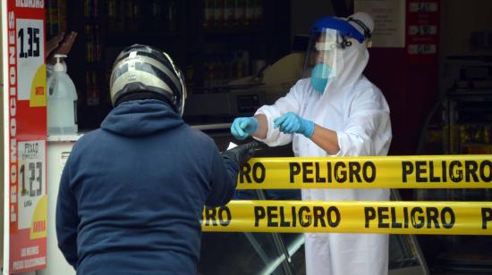 En el centro de Cuenca, un comerciante atiende con traje de seguridad el 27 de abril de 2020.