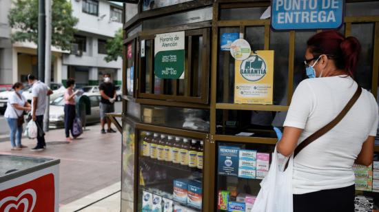 Una mujer aguarda en la ventanilla de entrega de productos de una farmacia de Guayaquil, el 15 de abril de 2020. 