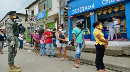 Un militar controla que los ciudadanos en Guayaquil respeten la distancia en una fila para entrar a un supermercado, el 20 de abril de 2020.