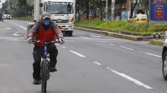 Un hombre con mascarilla circula a bordo de una bicicleta, en el norte de Quito; este lunes 4 de mayo de 2020, en el primer día del distanciamiento social.