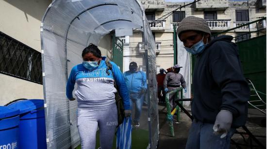 Personas pasan por un túnel de desinfección en el mercado de San Roque de Quito, el 10 de abril. 