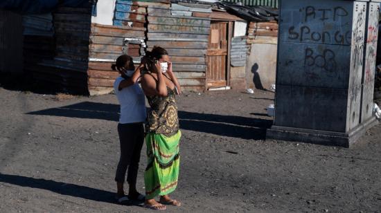 Una señora le coloca una mascarilla a otra, el 28 de abril de 2020, en Cape Town, Sudáfrica.